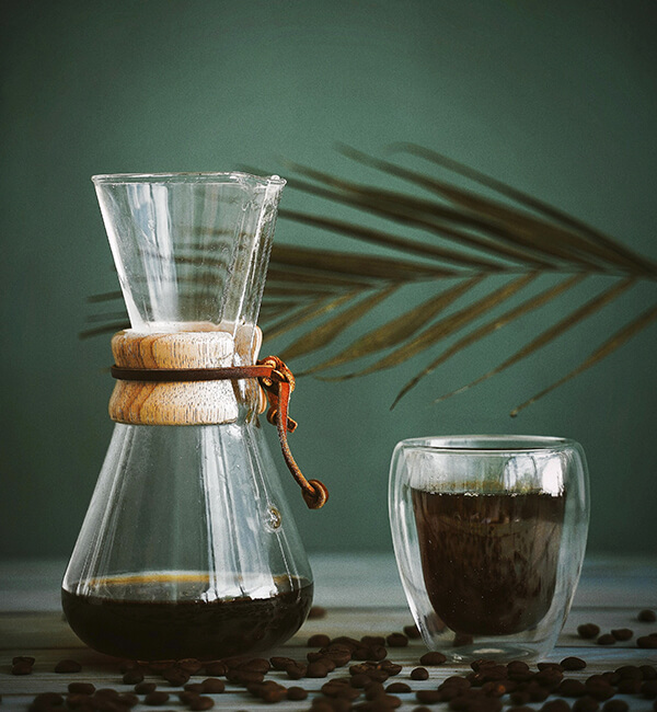 A pour-over coffee brewer beside a glass of coffee